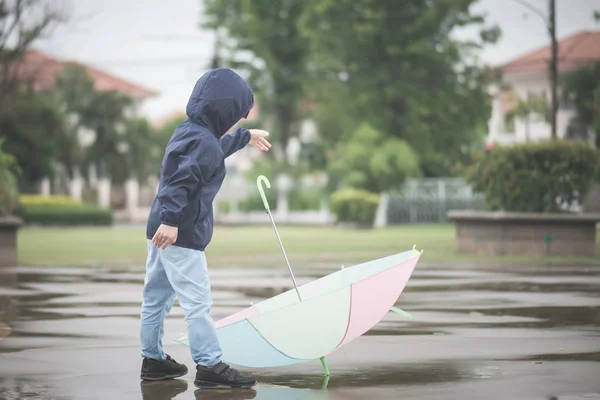 公園で遊ぶカラフルな傘を持って幸せなアジア少年 — ストック写真