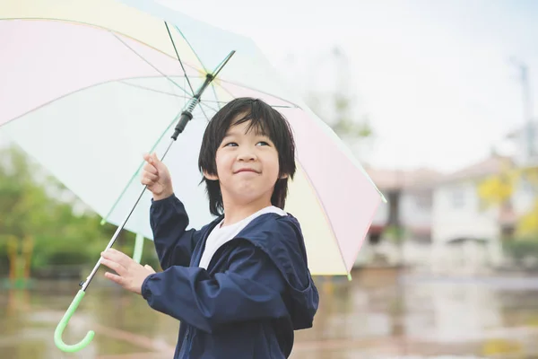 Heureux asiatique garçon tenue coloré parapluie jouer dans l 'parc — Photo