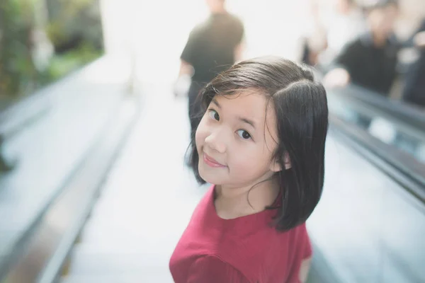 Menina asiática de pé na escada rolante — Fotografia de Stock