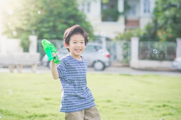 Azjatycki dziecko pęcherzyki strzelanie z pistoletu bańki — Zdjęcie stockowe