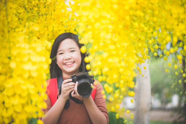 Aziatisch meisje neem foto met bloeiende gele bloem — Stockfoto