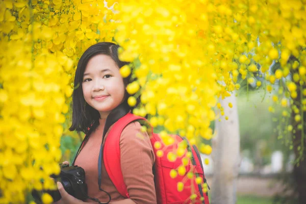 Asian girl take photo with blooming yellow flower — Stock Photo, Image