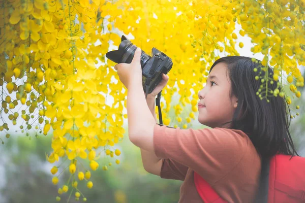 Asiatische Mädchen nehmen Foto mit blühenden gelben Blume — Stockfoto