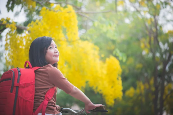 Красивая азиатка с красным рюкзаком на велосипеде в парке — стоковое фото