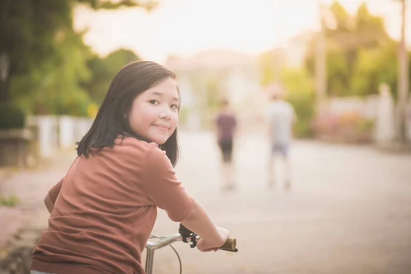 Chica asiática montando bicicleta en la luz del sol — Foto de Stock