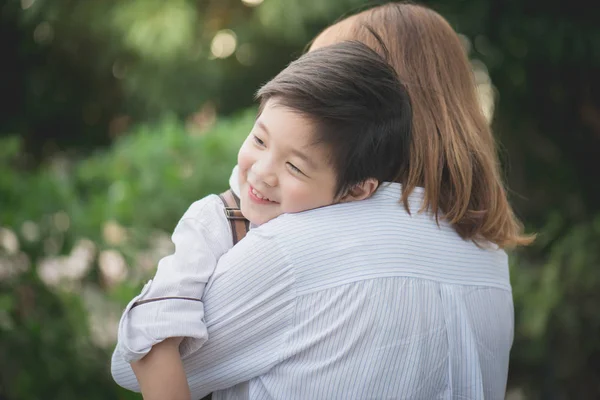 एशियाई माँ पार्क में अपने बेटे के साथ hugging — स्टॉक फ़ोटो, इमेज