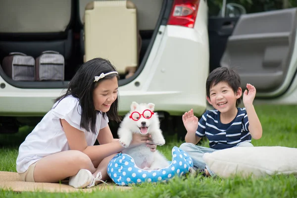 Asijské děti si hrají s sibiřský husky štěně — Stock fotografie