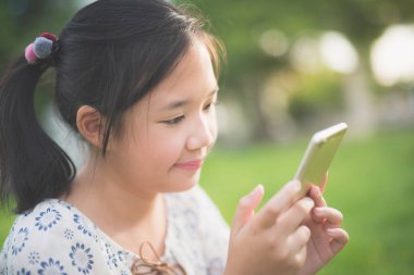 Sakin ol duygu ile akıllı telefon kullanan güzel Asyalı kız ve gülen yüz, açık