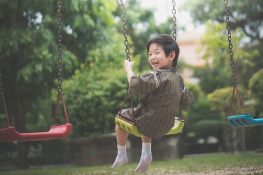 Parkta salıncak üzerinde oynarken kimono içinde şirin Asyalı çocuk