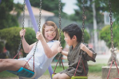 Asya anne ve oğlu parkta sallanan