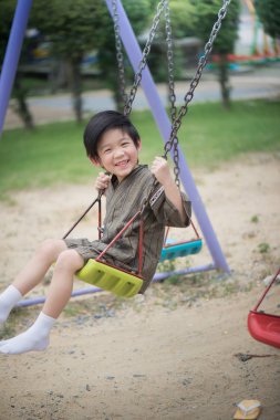 Parkta salıncak üzerinde oynarken kimono içinde şirin Asyalı çocuk
