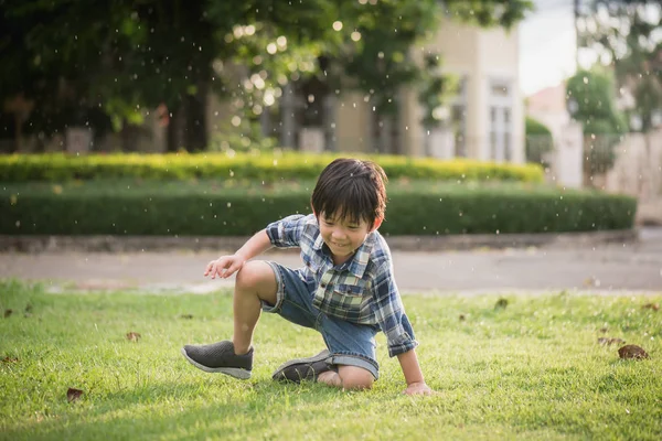 かわいいアジアの子が雨の中公園で遊んで — ストック写真