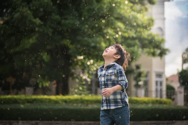雨の公園で見上げてかわいいアジアの子 — ストック写真
