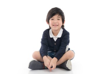 İzole beyaz arka plan üzerinde oturan mutlu Asyalı çocuk