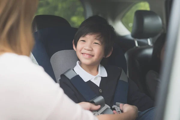 アジアの女性の車の安全シートベルトを持つ子供を固定 — ストック写真