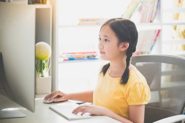 Güzel Asyalı kız masaüstü bilgisayarda çalışarak