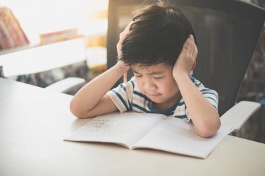 Mutsuz Asyalı çocuk üzerinde sabit ödev evde tek başına çalışıyor
