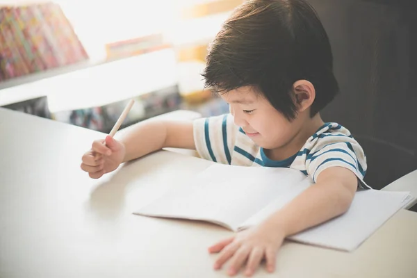 Lite Asiatiska Barn Använda Penna För Att Skriva Anteckningsboken Vid — Stockfoto