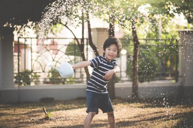 Şirin Asyalı çocuk yaz günü bahçede sulama