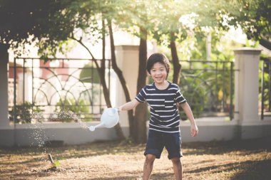 Şirin Asyalı çocuk yaz günü bahçede sulama