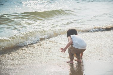 Kumsalda oynarken sevimli Asya çocuk arkası
