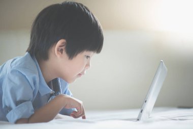 Yatakta yatan ve beyaz yatakta dizüstü kullanarak Asya yakışıklı
