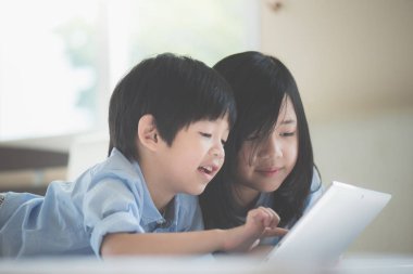 Yatakta yatan ve beyaz yatakta dizüstü kullanarak sevimli Asya çocuk