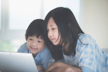 Yatakta yatan ve beyaz yatakta dizüstü kullanarak sevimli Asya çocuk