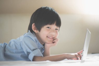 Yatakta yatan ve beyaz yatakta dizüstü kullanarak Asya yakışıklı