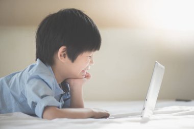 Yatakta yatan ve beyaz yatakta dizüstü kullanarak Asya yakışıklı