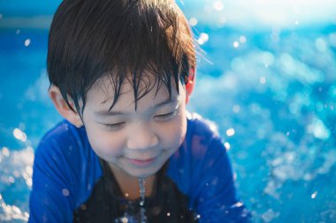 Tatlı Asyalı çocuk yüzüyor ve havuzda oynuyor.