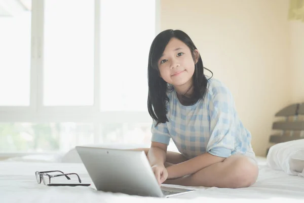Ασιατικό Χαριτωμένο Κορίτσι Κάθεται Στο Κρεβάτι Και Χρησιμοποιούν Φορητό Υπολογιστή — Φωτογραφία Αρχείου