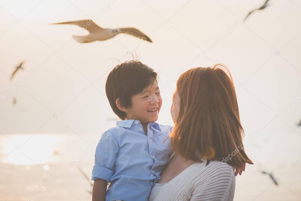 Happy Asian mother and son playing on the beach
