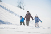 Asijské otce a jeho děti, drželi se za ruce a společně procházky ve sněhu