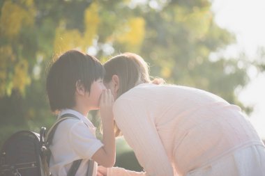 Asyalı çocuk annesi, okul için bir şeyler fısıldıyor