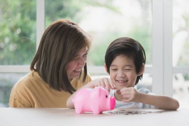 Yazı tura bir kumbara koyarak şirin Asyalı çocuk