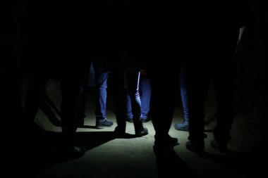 Yeraltı karanlığında gizli bir grup ayak buluşması, bir fener tarafından vurgulanan gizemli bir takipçi, gece zindanda gizli bir toplantı.