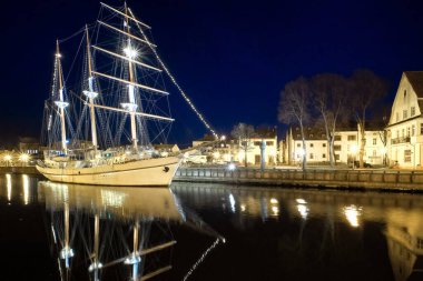 Yelkenli teknesi Litvanya 'nın Klaipeda şehrinde demir attı ya da demir attı. Ortaçağ kasabası ve barquentine sakin sularda yansıması.