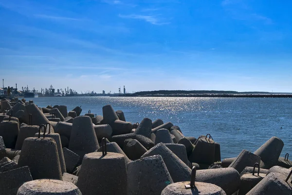 Blick auf einen Hafen über modulare Betonklötze im Vordergrund und Hafen im Hintergrund an sonnigen Tagen. Hafendeich am Meer. — Stockfoto