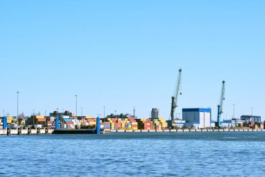 Açık güneşli bir günde, iskele vinçlerini, köprüleri ve konteyner terminalini ve bulutsuz gökyüzünü görmek. Deniz ticareti, ulaşım, ticaret ve kargo