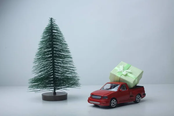 Nep kerstboom en een pick-up met een kerstcadeau op lichte achtergrond — Stockfoto