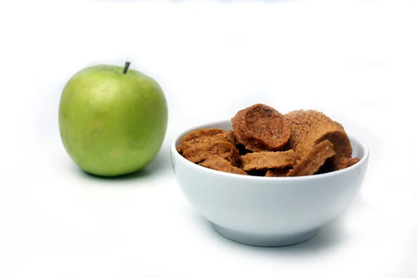 Grüner Apfel und eine Schüssel mit Fruchtbonbons auf weißem Hintergrund — Stockfoto