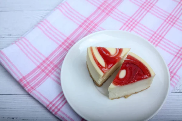 Zwei Stücke Käsekuchen auf einem Teller auf Tischdecken auf weißem Holzhintergrund flach gelegt — Stockfoto