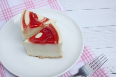 Tabakta iki parça cheesecake ve beyaz ahşap zemin üzerinde masa örtüleri üzerinde bir çatal.