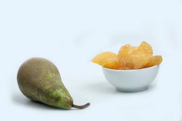 Ένα μπολ με αποξηραμένα αχλάδια και ένα πράσινο αχλάδι που απομονώνεται σε λευκό φόντο. Οριζόντια εικόνα — Φωτογραφία Αρχείου