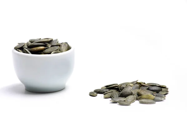 Миска і купа насіння гарбуза ізольовані на білому тлі. Горизонтальне зображення — стокове фото