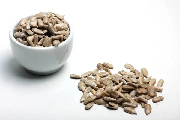 Una ciotola e una pila di semi di girasole isolati su sfondo bianco posa piatta. Immagine orizzontale — Foto Stock