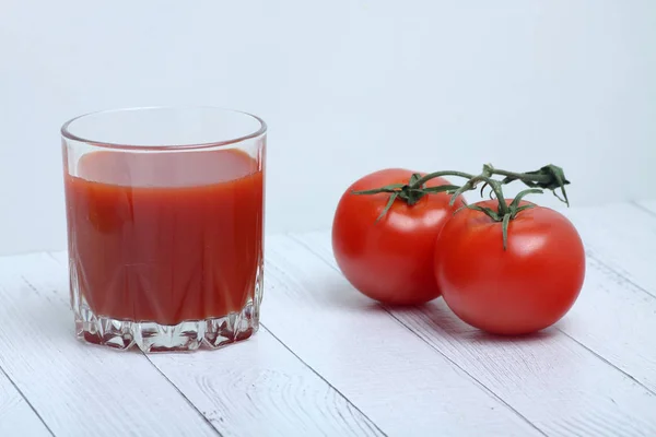 Ein Glas Tomatensaft und Tomaten isoliert auf weißem Holz Backgrond. horizontales Bild — Stockfoto
