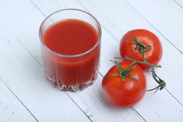 Ein Glas Tomatensaft und Tomaten lagen isoliert auf einem hölzernen Backgrond flach. horizontales Bild — Stockfoto