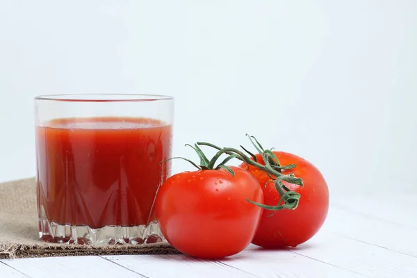 Ein Glas Tomatensaft und Tomaten auf Leinwand-Tischdecke auf weißem Holzbackgrond. horizontales Bild — Stockfoto